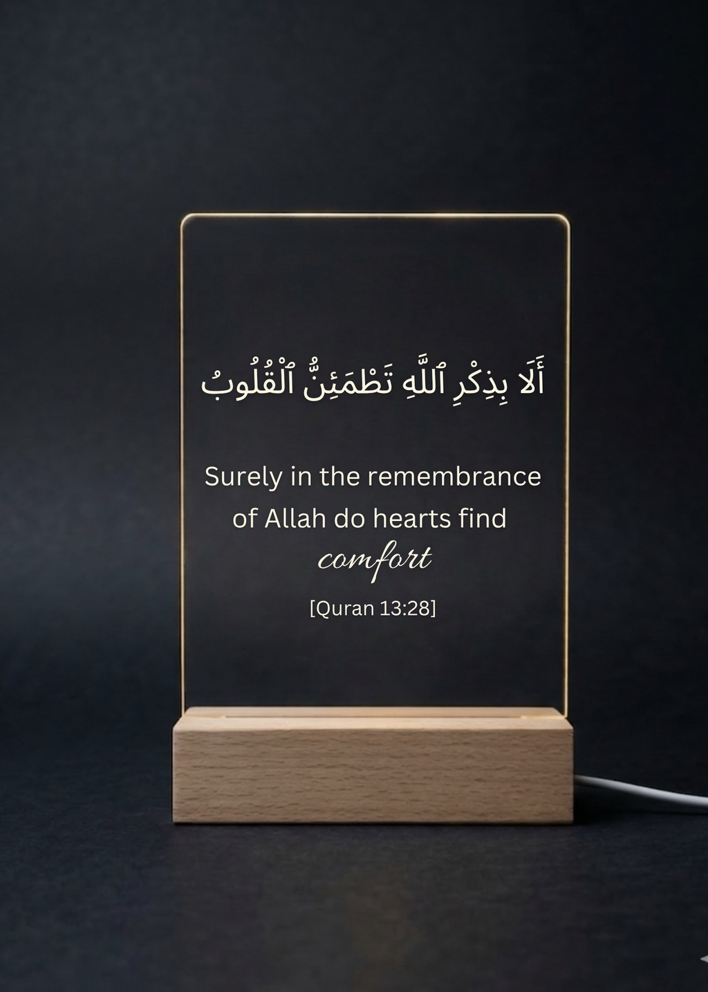 Acrylic sign with Quran verse on a wooden stand against a dark background