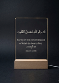 Acrylic sign with Quran verse on a wooden stand against a dark background