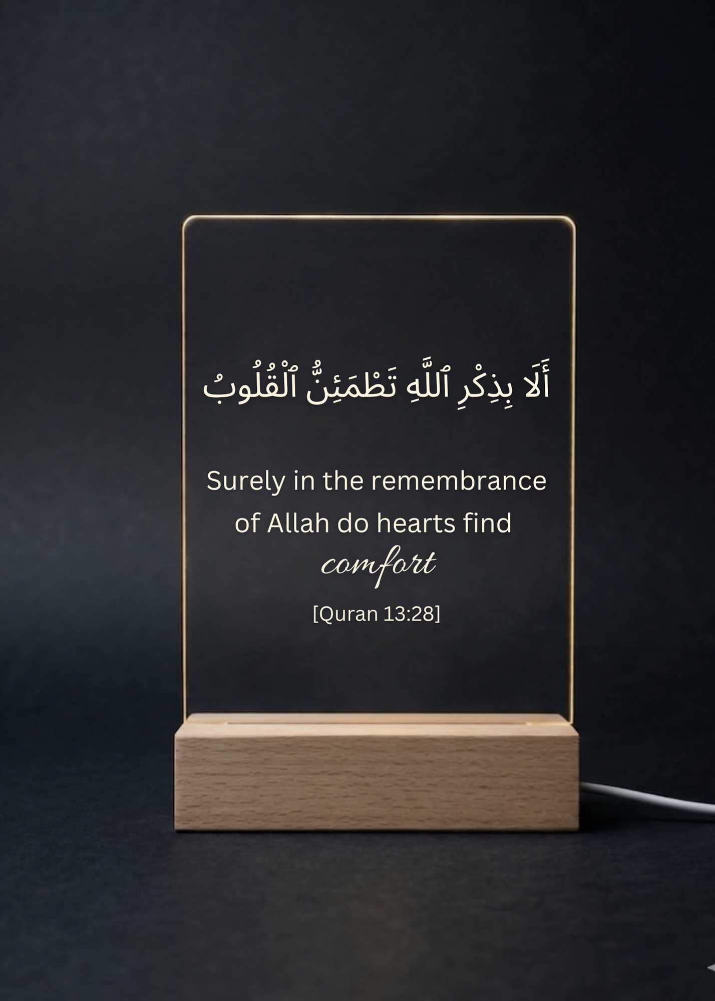 Acrylic sign with Quran verse on a wooden stand against a dark background