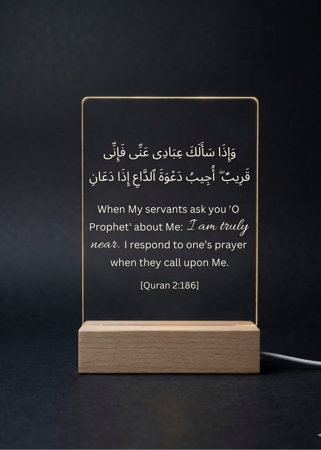 Acrylic sign with Quran verse on a wooden stand against a dark background