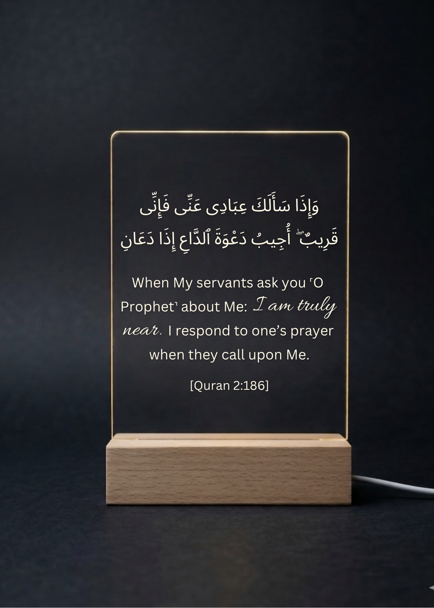Acrylic sign with Quran verse on a wooden stand against a dark background