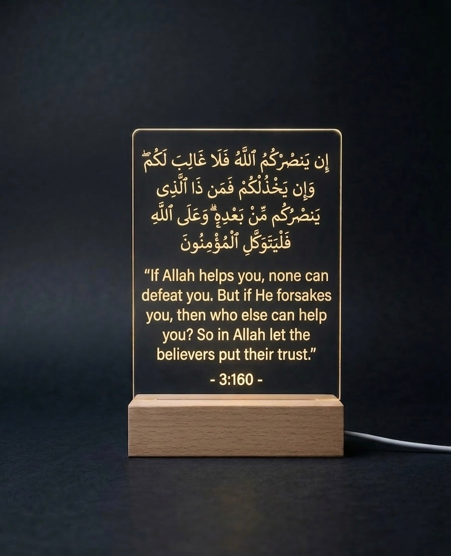 LED sign with Arabic text and English translation on a wooden base against a dark background