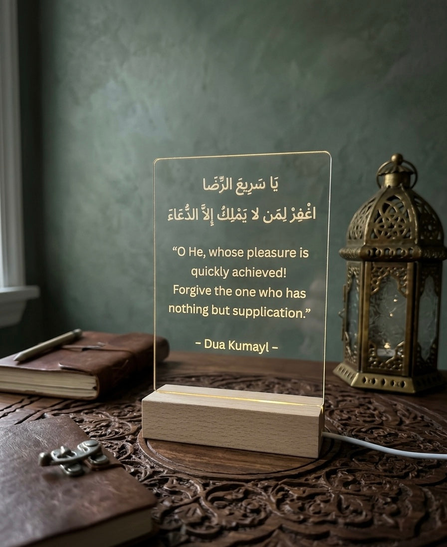 Acrylic plaque with Arabic text on a wooden stand, surrounded by books and a lantern.