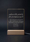 Acrylic plaque with Arabic text and English translation on a wooden stand against a dark background