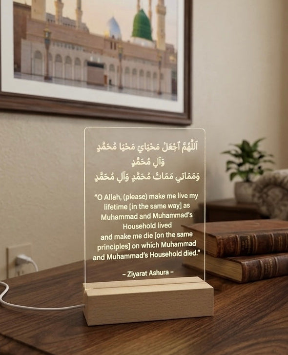 Acrylic lamp with engraved text on a wooden table in a room with a framed picture of a mosque.